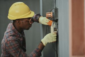 A man in a hardhat inspects an electrical system.