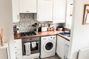 A photograph of a small, cramped kitchen with a washing machine in it.