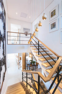 A beautiful iron and wood staircase ascends to a second-story addition.