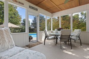 A sunroom with several windows that looks out onto a pool.