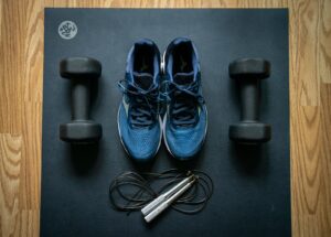 Photo of sneakers, weights, and a jumproap on a yoga mat.