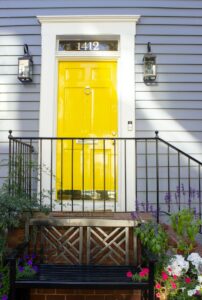 A photo of a yellow front door behind an iron railing.