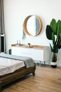 A photo of a bedroom with a mirror above a dresser.