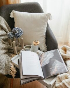 A photo of a chair with pillows and an open book.
