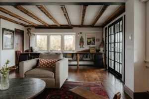 A photograph of a living room with exposed wooden beams on the cieling.